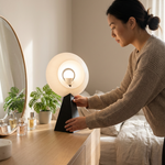 Woman adjusting a lamp on a dresser in a bedroom setting
