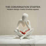 White abstract sculpture holding a red book on a light surface with text above.