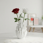 White vase with red and white roses on a light surface with a minimal background