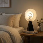 Decorative table lamp on a nightstand next to a bed with pillows