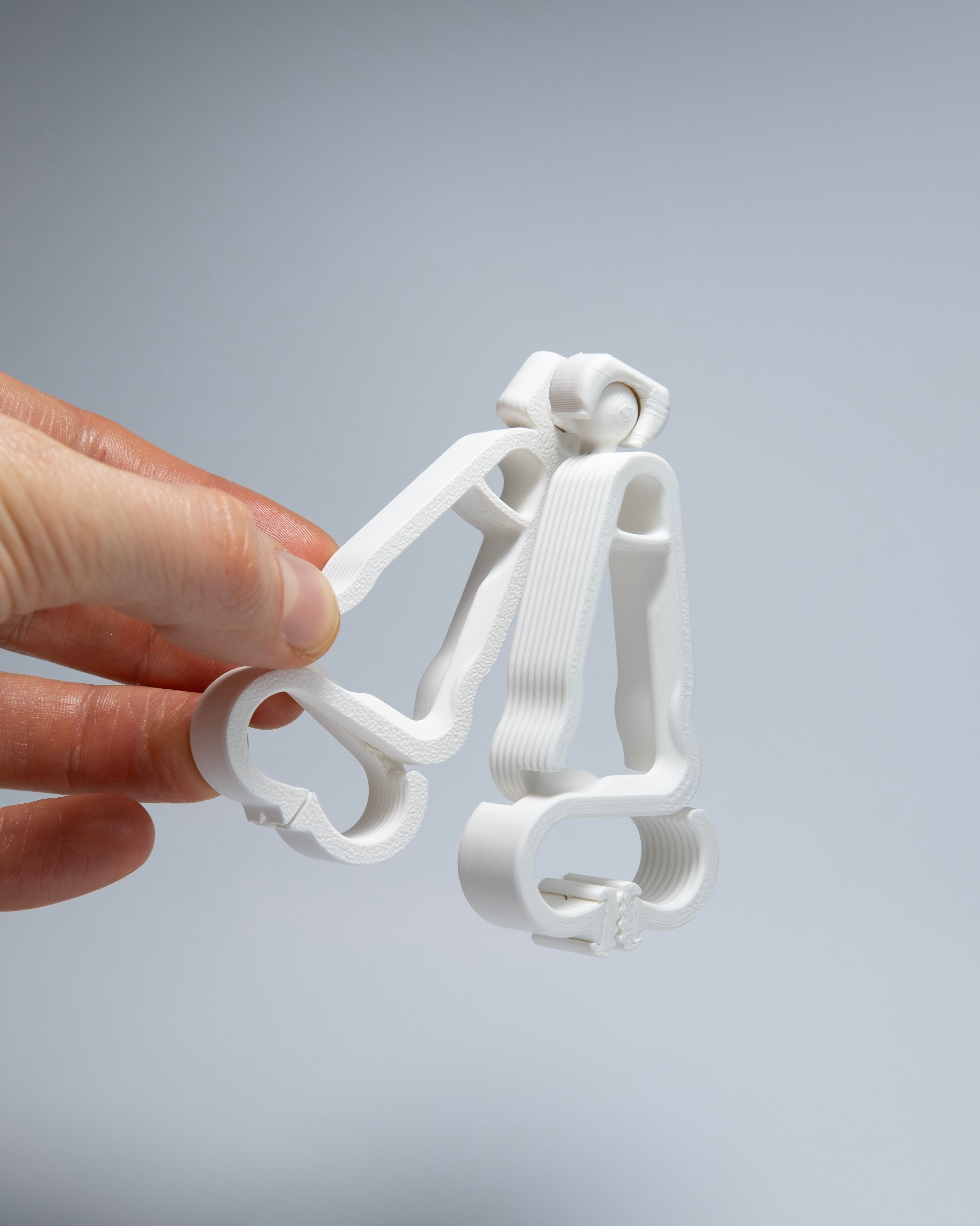 Hand holding a white plastic clip against a gray background