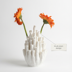 White textured vase with orange flowers on a light gray background
