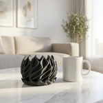Black decorative bowl and white mug on a marble table in a living room.