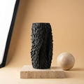 Black textured vase on a beige platform with a neutral background