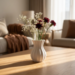 White vase with flowers on a wooden table in a living room