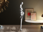 side of Abstract sculpture on a wooden table with a dark wall and framed pictures in the background