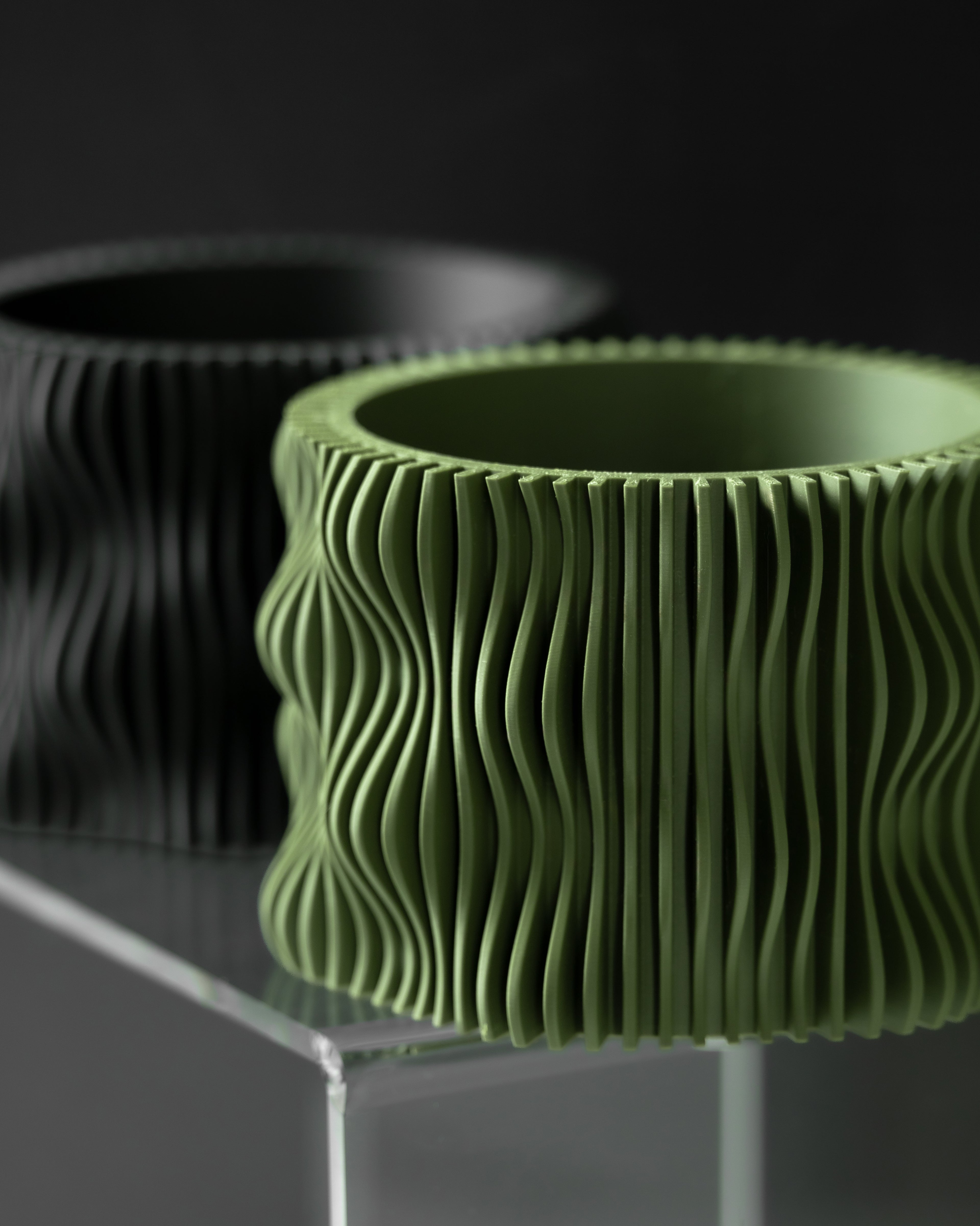 Olive Green textured planter on a clear stand with a dark background