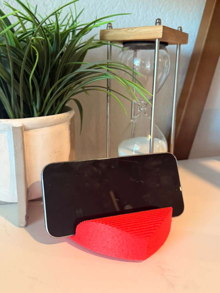 Phone on a red stand with a plant and lamp in the background