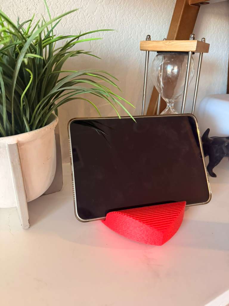 Tablet on a red stand with a plant and hourglass in the background