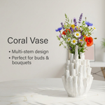 White coral vase with colorful flowers on a marble surface