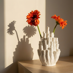 White textured vase with red flowers on a wooden surface