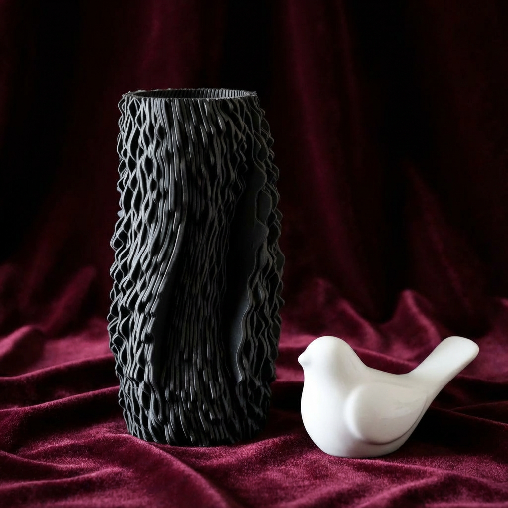 Black textured vase and white ceramic bird on a red fabric background