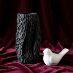 Black Organic Ribbed Tall Vase beside a white bird figurine on burgundy fabric