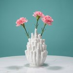 White textured vase with pink flowers against a teal background