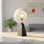 Halo N1 lamp glowing warm yellow through its white circular shade on a marble living room table
