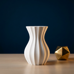 White Modern Fluted Vase beside a gold-colored geometric ornament on a wooden surface
