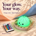 Dumpling lamp ad reading 'Your glow, your way': a cute night light glowing green in its steamer basket with chopsticks, next to a color remote with rows of buttons.