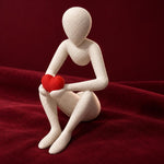 White Love’s Embrace figure holding a red heart against burgundy fabric