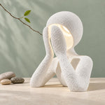 White NObody Lamp on a pale tabletop with stones and a green backdrop