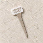 White and beige plant marker labeled African Violet, with a wavy neck and pointed stake