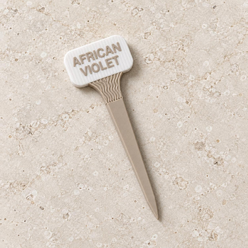 White and beige plant marker labeled African Violet, with a wavy neck and pointed stake