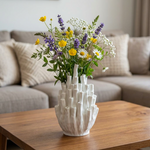 White textured vase with flowers on a wooden table in a living room setting