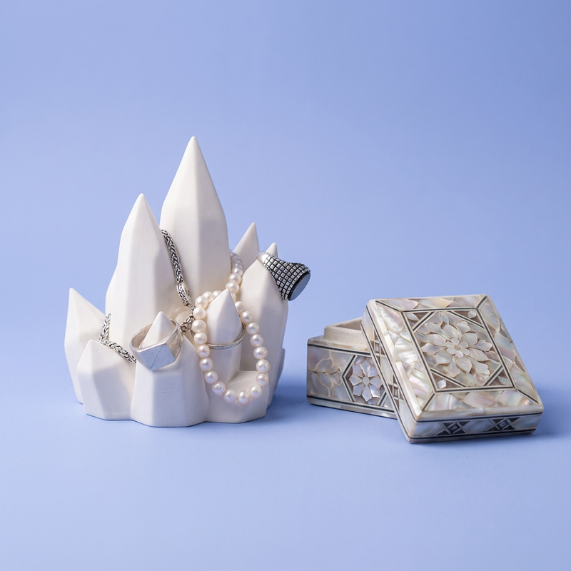 White Crystal Cluster Jewelry Holder with rings and necklaces beside a decorative box on a light blue background