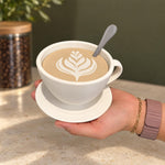 White coffee cup storage container with spoon held beside a coffee jar