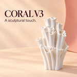White matte textured coral-shaped vase on a soft peach backdrop with the text "CORAL V3 A sculptural touch." in dark purple, a sculptural vase with ruffled tubular openings.