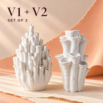Two white matte textured coral-style vases with the text "V1 + V2 SET OF 2" at the top, a pair of tubular sculptural vases on a peach backdrop.