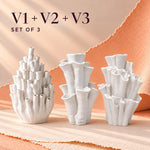 Three white matte textured coral-style vases of different heights with the text "V1 + V2 + V3 SET OF 3" above them, a sculptural vase trio on a peach backdrop.
