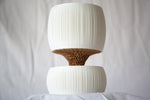 Low-angle view of the empty Pallas planter with its tan wavy core between two white ribbed sections