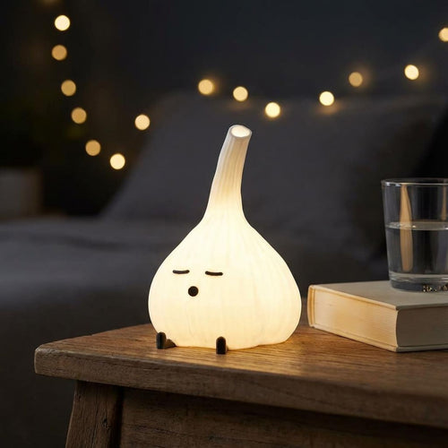 Glowing garlic lamp on a dark bedside table beside a glass and string lights