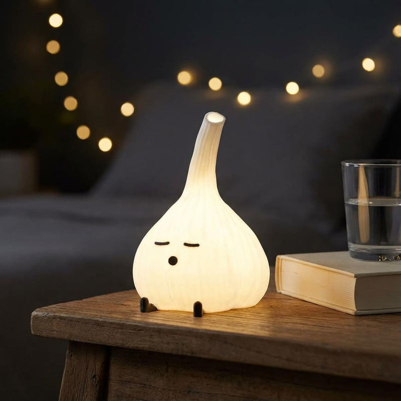 Glowing garlic lamp on a dark bedside table beside a glass and string lights