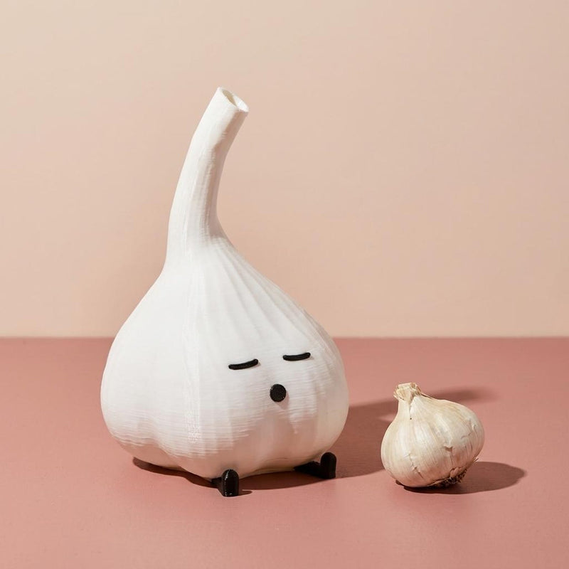 Classic white garlic lamp beside a garlic bulb on a pink background