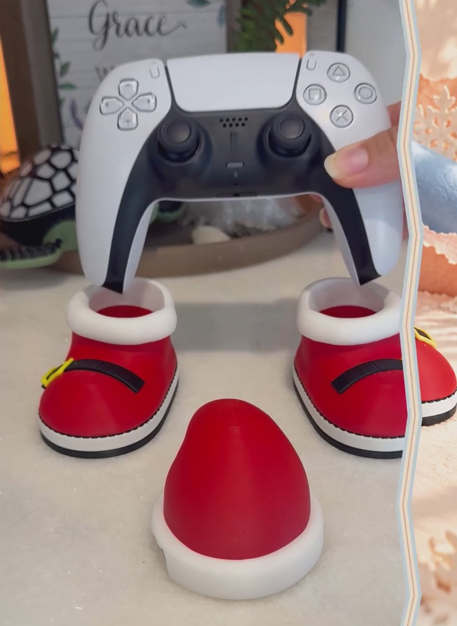 Santa controller stand video: red Santa boots and Santa hat set up to hold a game controller, a christmas gamer gift.