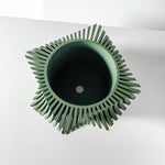 Top view of the green ribbed planter showing its round interior and central drainage hole.